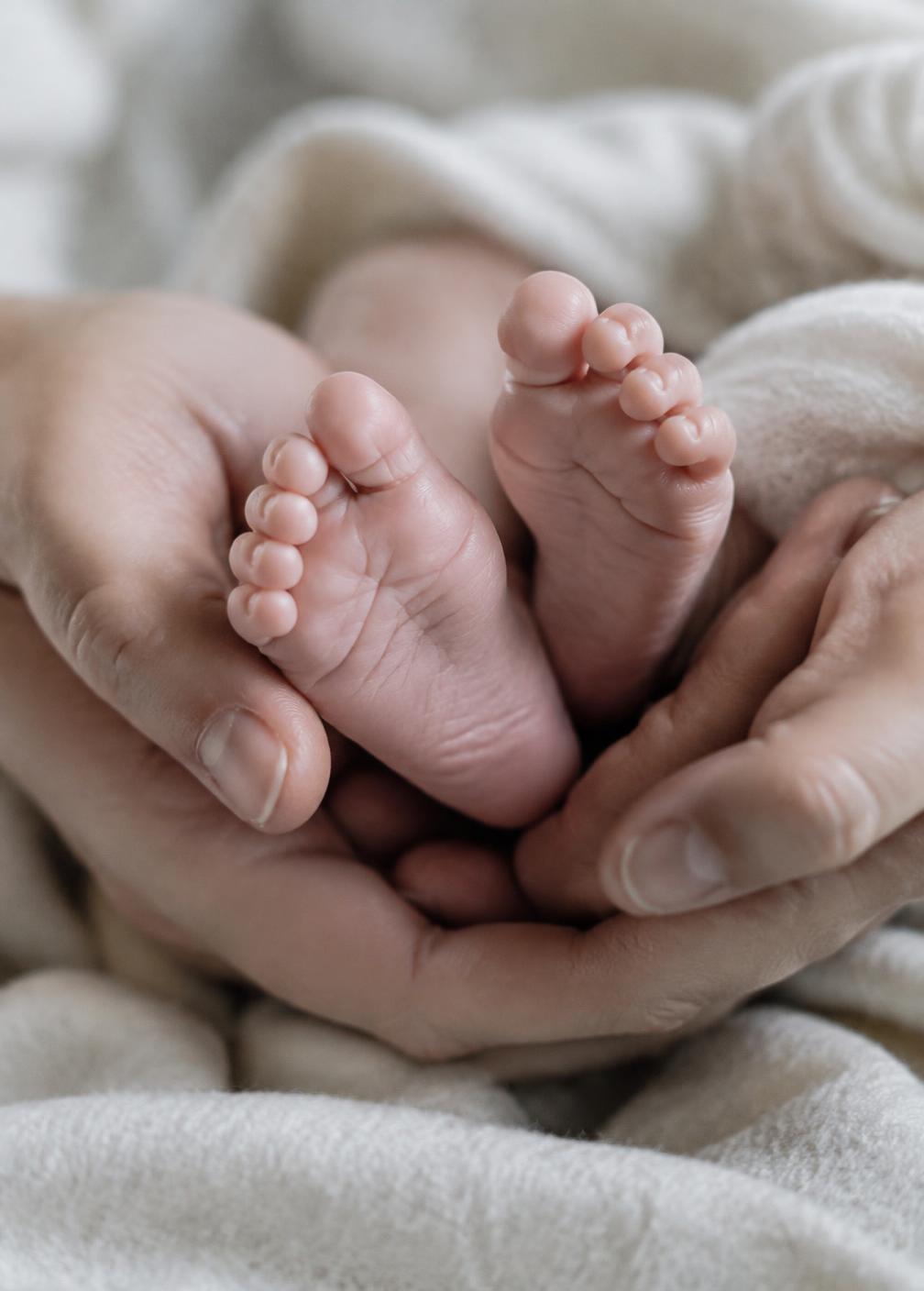 Tiny newborn feet cradled in a parent's hands
