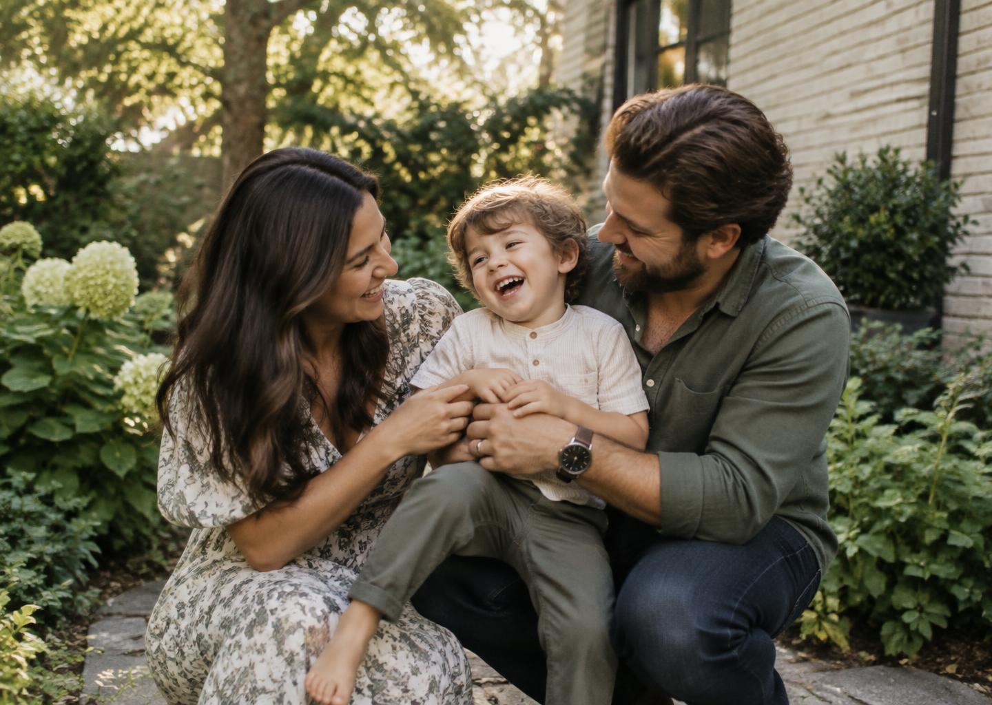 Parents laughing with their child in the garden of their home